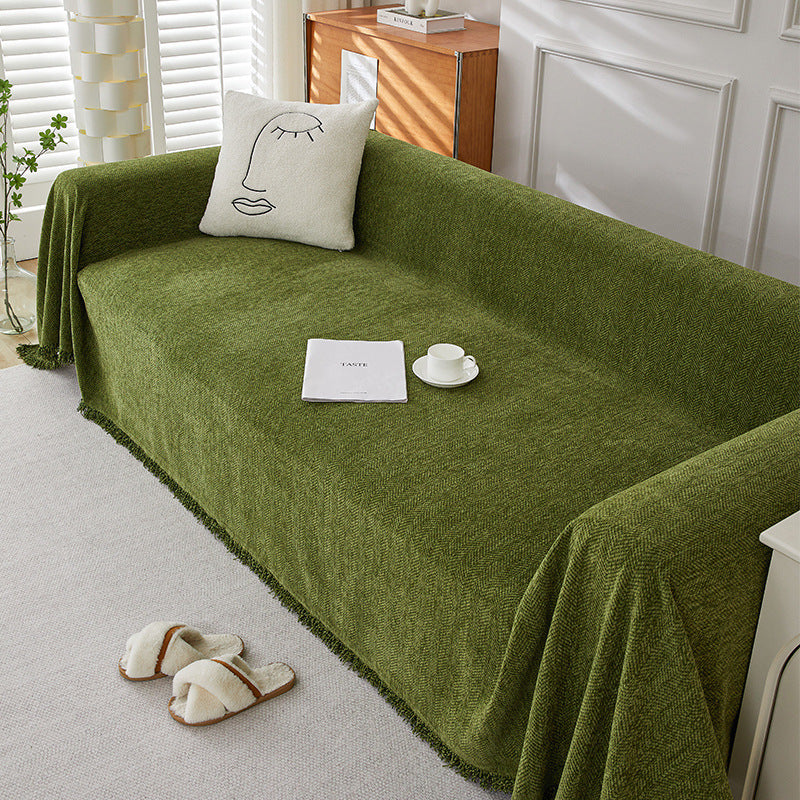 Textured green herringbone chenille sofa cover with minimalist pillow and cozy slippers