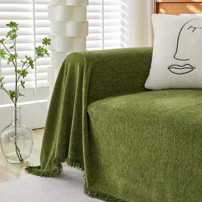 Green herringbone chenille sofa cover with abstract face pillow in sunlit living room