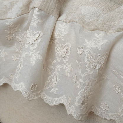 Close-up of textured linen cotton fabric with embroidered butterfly and floral trim in neutral tones