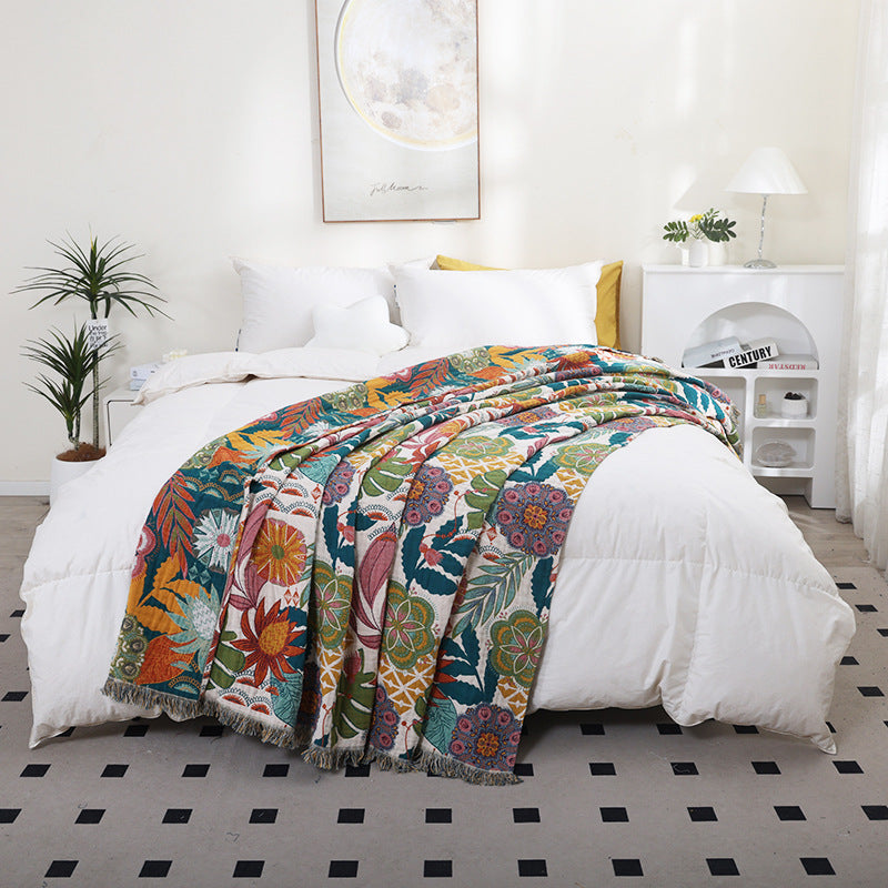 Colorful tropical floral cotton throw blanket covering a bed with fringe edges