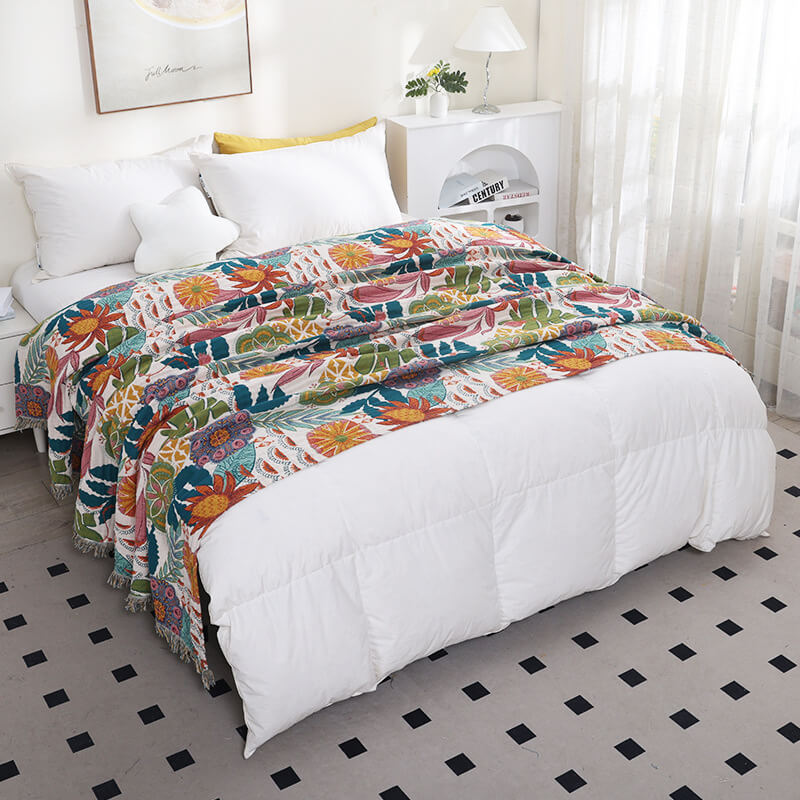 Tropical floral cotton throw blanket draped across a white bed with botanical pattern