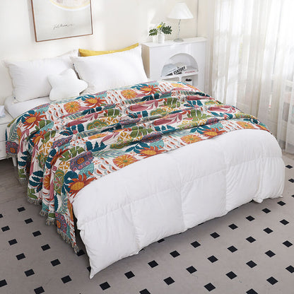 Tropical floral cotton throw blanket draped across a white bed with botanical pattern