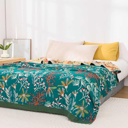 Vintage botanical floral cotton throw blanket in deep teal with colorful wildflower patterns spread across a bed.