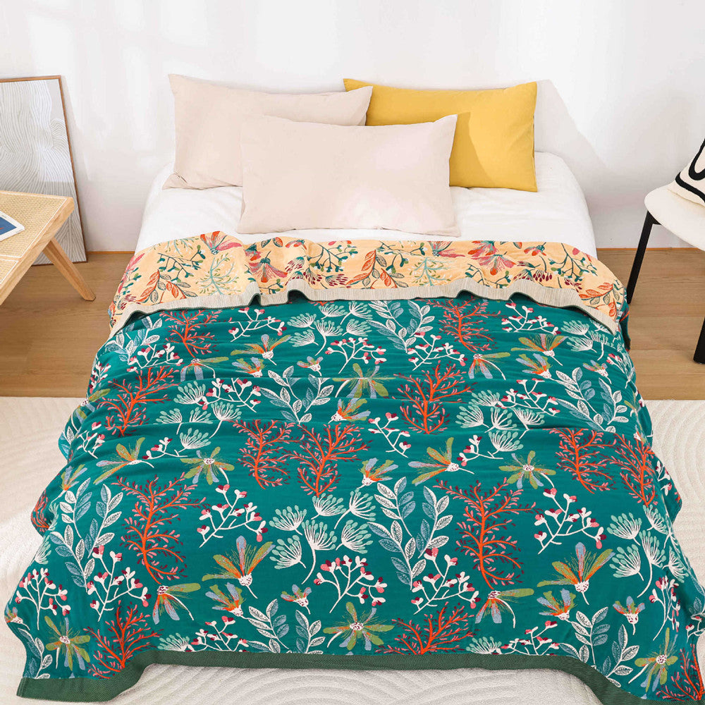 Full top-down view of a reversible teal botanical cotton blanket featuring intricate orange and white floral patterns.