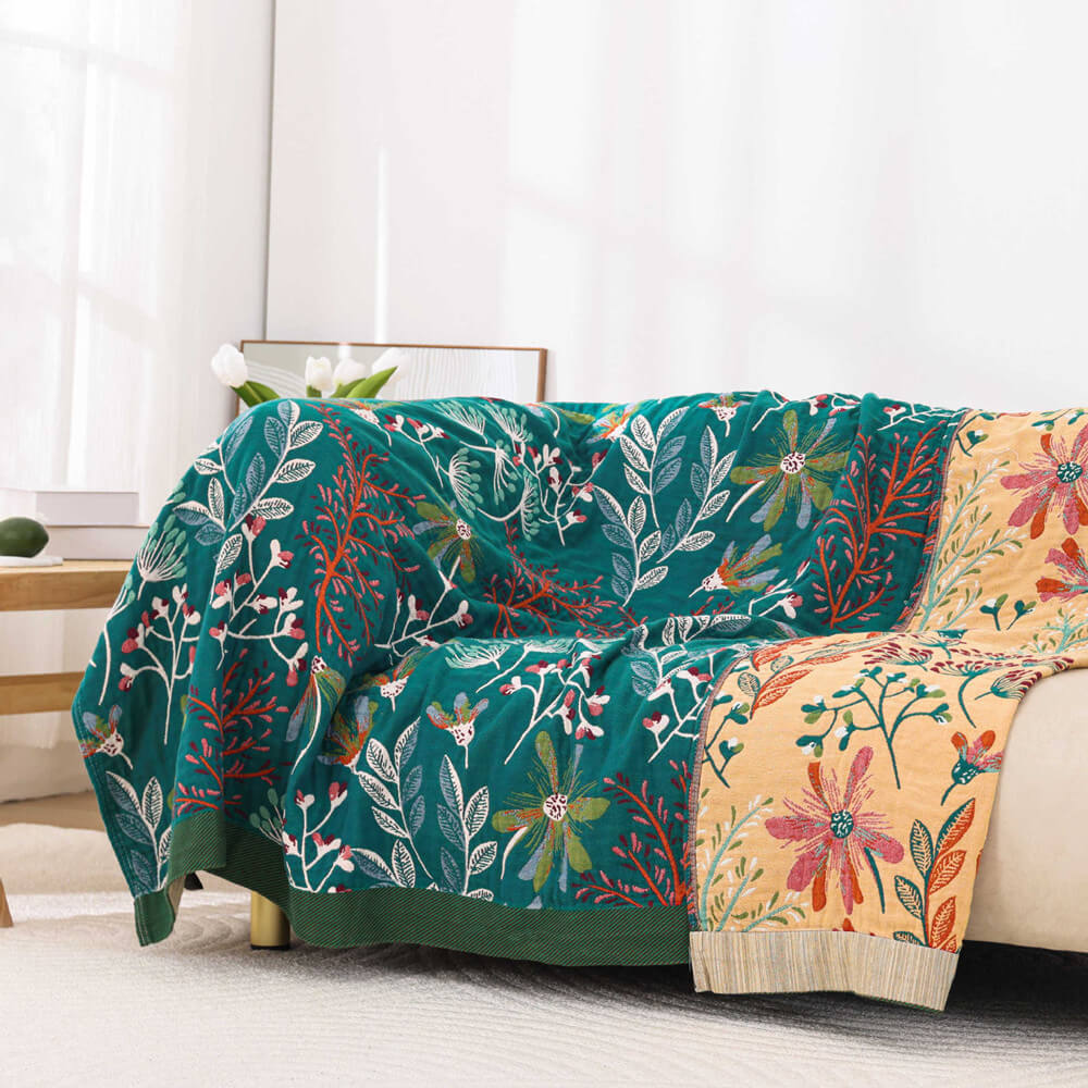 Reversible vintage floral throw blanket draped over a modern sofa, showcasing both the teal and cream botanical sides.