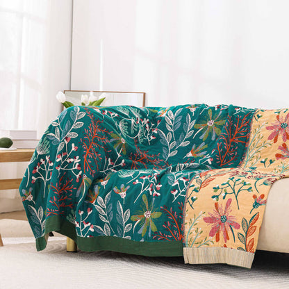 Reversible vintage floral throw blanket draped over a modern sofa, showcasing both the teal and cream botanical sides.