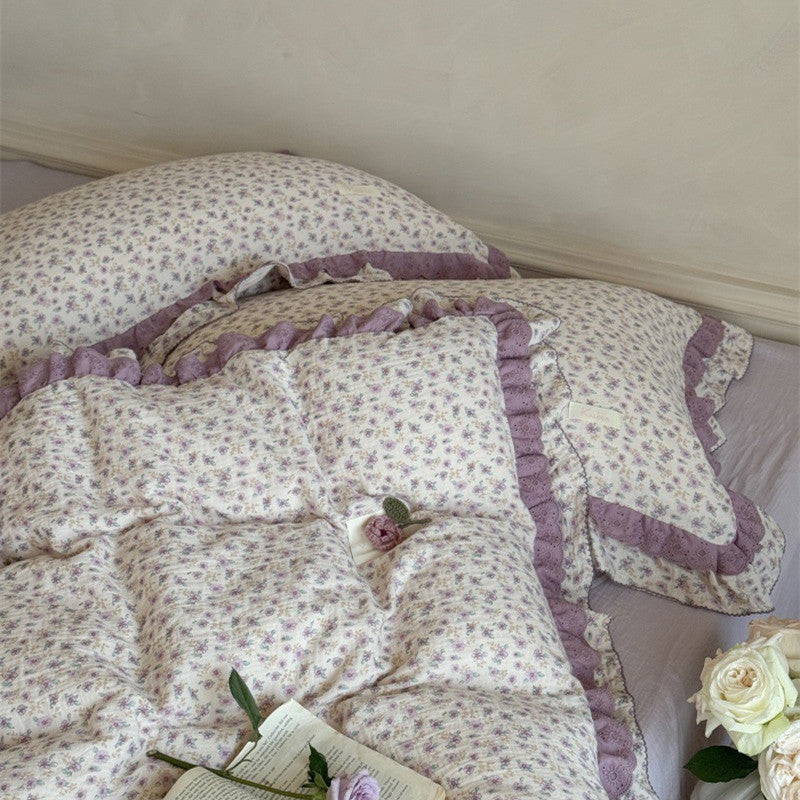 Detailed view of the layered pillows and duvet cover surface, highlighting the rustic lavender floral print and premium stitching of the cottagecore bedding.