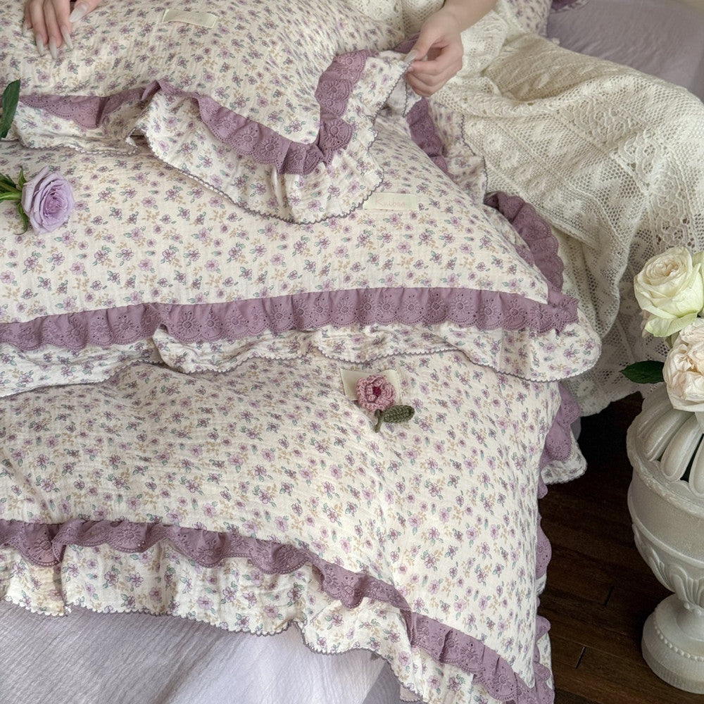 Close-up shot of the ruffled eyelet lace trim on the purple floral pillow shams, emphasizing the delicate embroidery and high-quality vintage French design.
