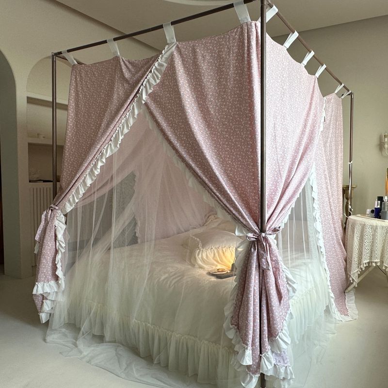 Vintage pink floral bed canopy with ruffled trim over white cotton bedding in a cozy bedroom