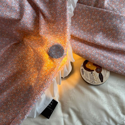Vintage floral pink bed canopy with white ruffled trim on cotton bedding, soft lighting