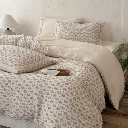 Side view of a country-style floral summer blanket flipped over to show its solid cream-colored textured cotton underside.
