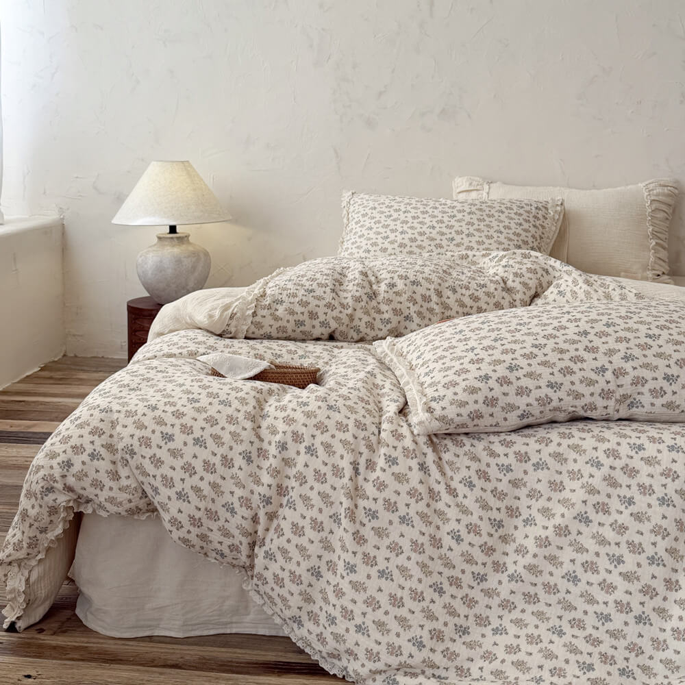 High-angle view of a vintage bed with a rustic floral comforter with eyelet lace borders.
