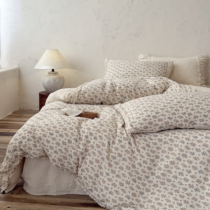 High-angle view of a vintage bed with a rustic floral comforter with eyelet lace borders.