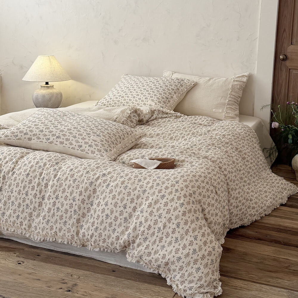 Front view of a beautifully styled cottagecore bed with a lightweight vintage floral comforter and a small decorative rattan basket.