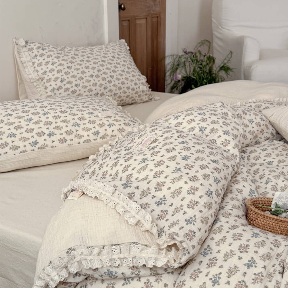 High-angle shot of a styled rustic bed with a breathable cotton-linen vintage floral summer blanket with eyelet lace edges.