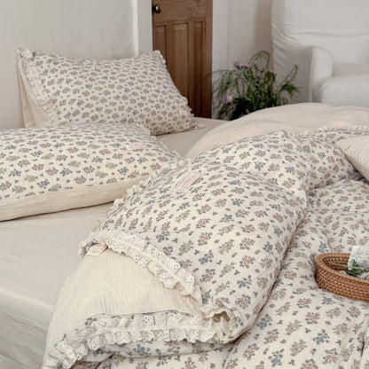 High-angle shot of a styled rustic bed with a breathable cotton-linen vintage floral summer blanket with eyelet lace edges.