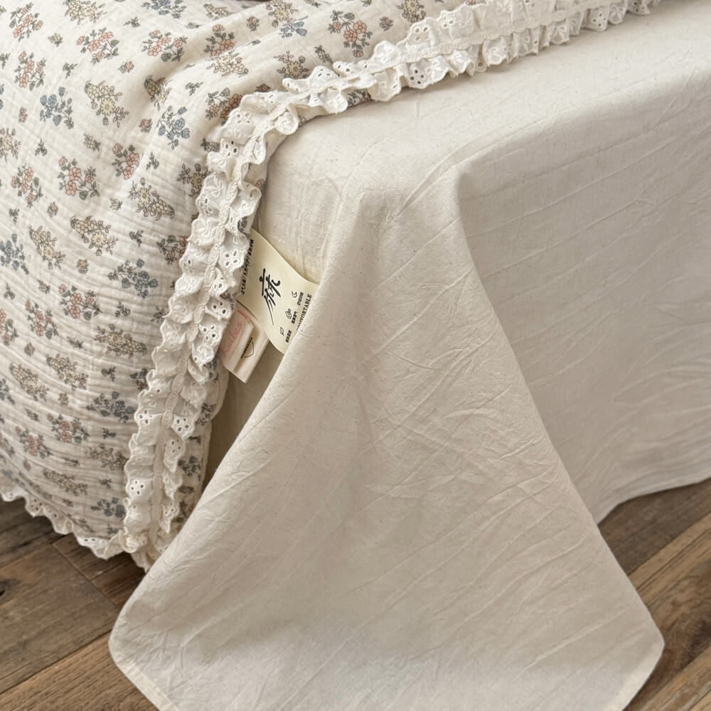 A detailed close-up shot of a rustic pillow with tiny floral patterns and sweet eyelet lace ruffle trim.