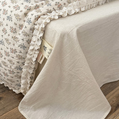 A detailed close-up shot of a rustic pillow with tiny floral patterns and sweet eyelet lace ruffle trim.