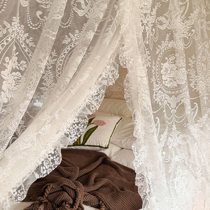 Decorative lace curtain with a floral pattern in a bedroom setting.