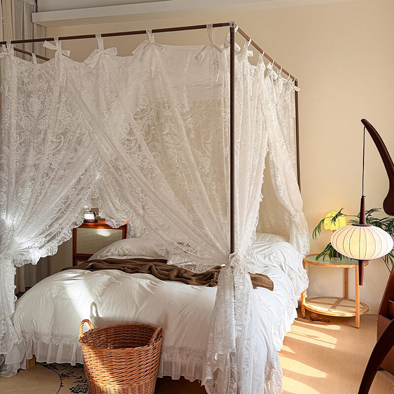 Bedroom with a canopy bed draped in lace curtains, wooden nightstands, and a lamp.