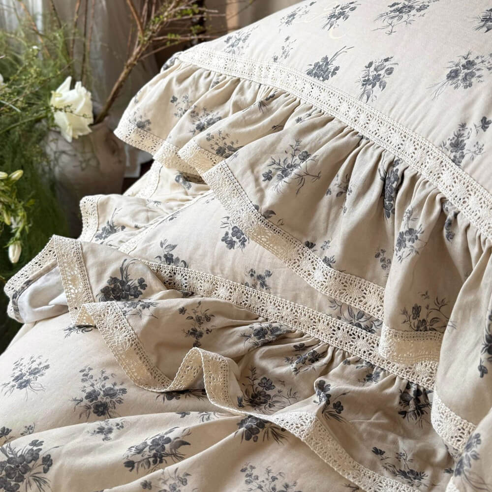 Detailed craftsmanship of the embroidered lace trim on a grey vintage floral muslin bedding set.