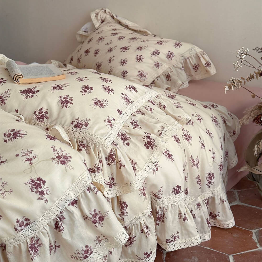 Detail view of the ruffled lace trim and breathable muslin fabric texture of the vintage rose bedding collection.