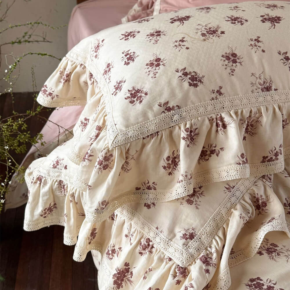 Stacked vintage rose muslin pillows showing the intricate lace trim and soft floral print details.