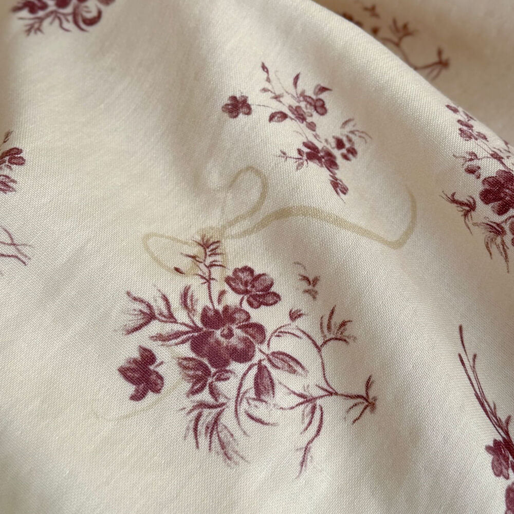 Macro shot of the high-quality muslin cotton fabric with a vintage rose floral print and ribbon motif.