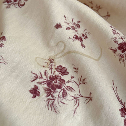 Macro shot of the high-quality muslin cotton fabric with a vintage rose floral print and ribbon motif.
