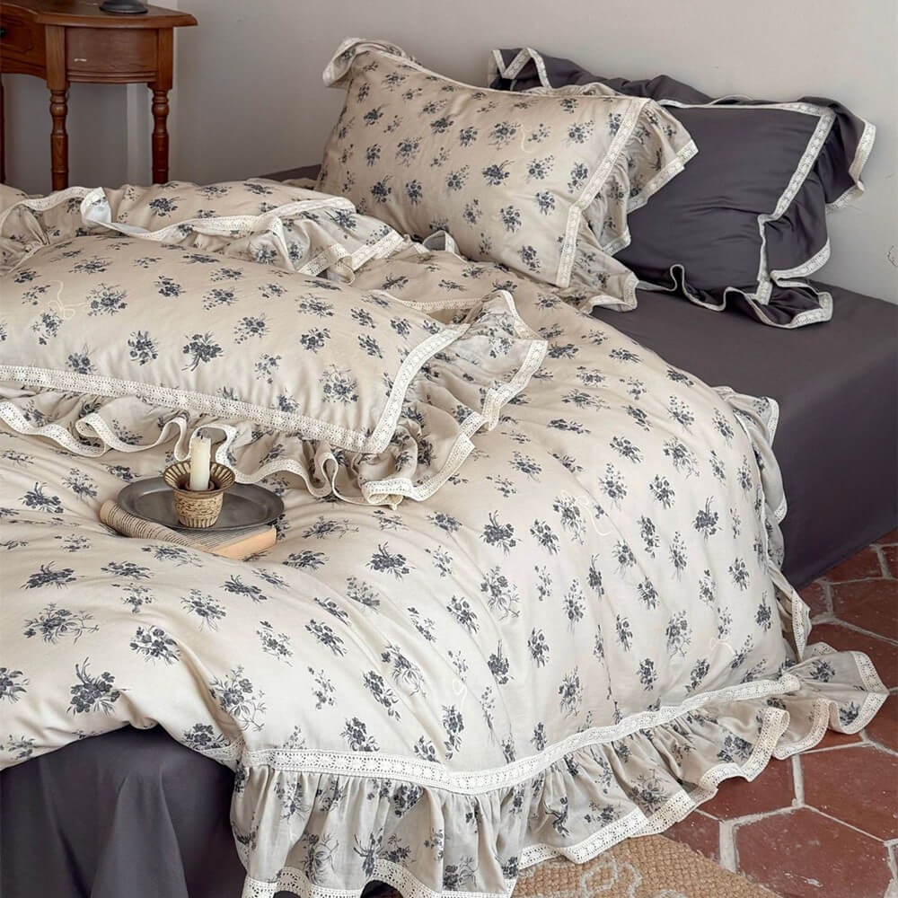 Full view of the grey vintage rose muslin bedding set with lace trim elegance on a rustic tile floor.