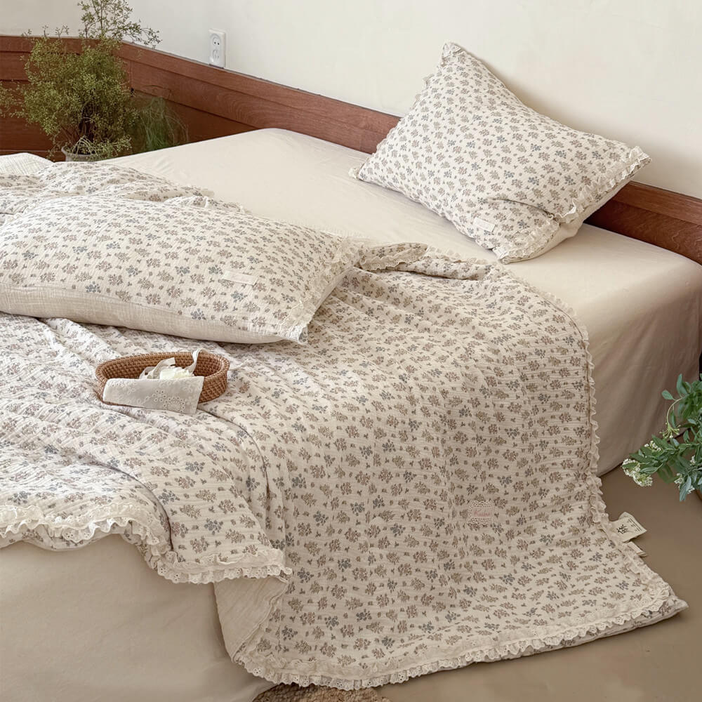 High-angle view of an inviting bed showcasing a lightweight French country floral quilt with ruffled lace borders.