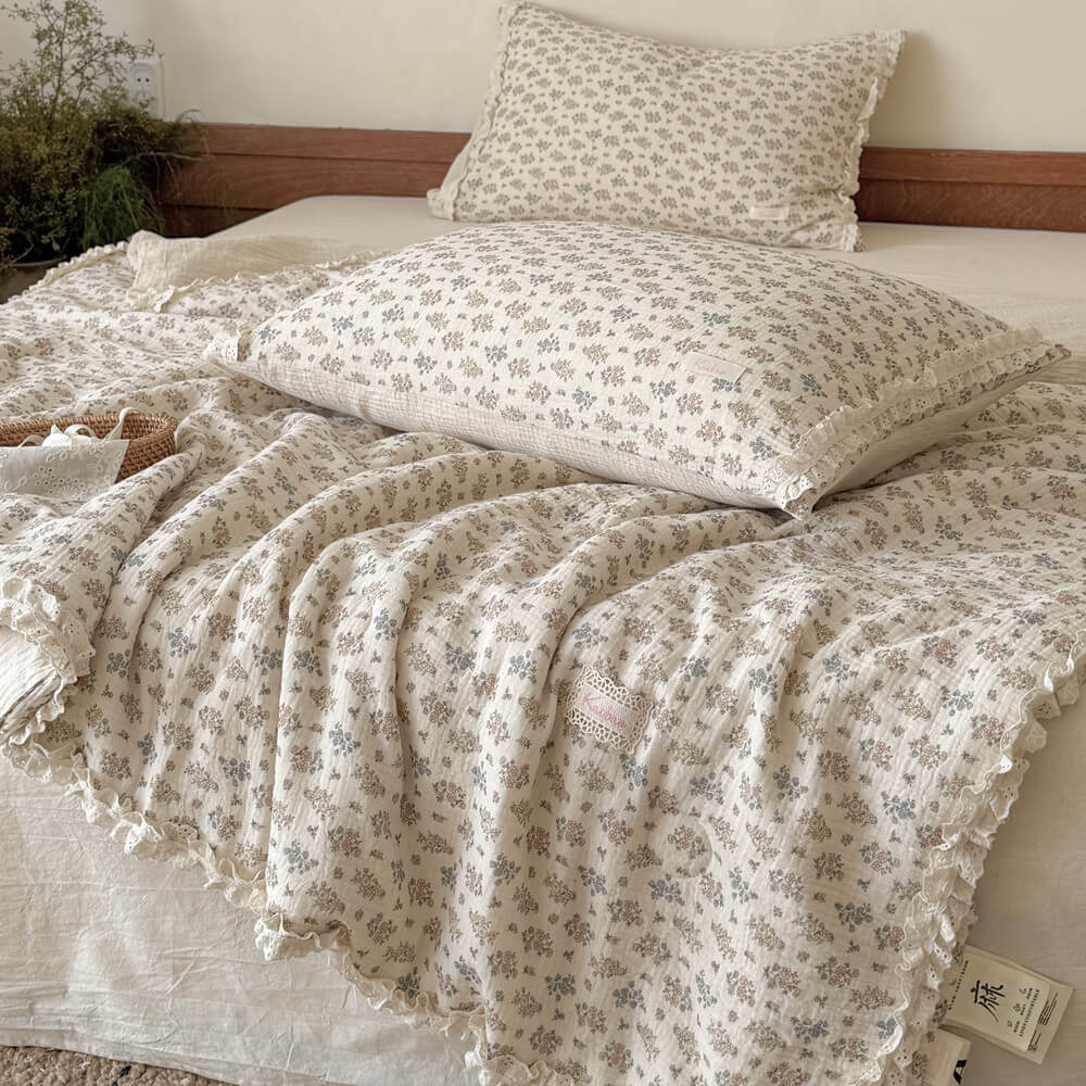 Close-up of a soft, crinkled cotton vintage floral summer comforter with detailed eyelet lace trim and a small logo patch.