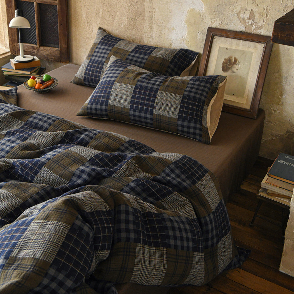 Bed with plaid bedding and pillows in a rustic bedroom setting.