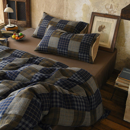 Bed with plaid bedding and pillows in a rustic bedroom setting.