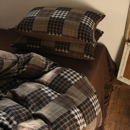 Plaid patterned pillows and duvet cover  on a bed against a neutral wall.