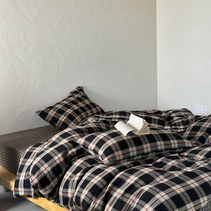 A cozy bedroom scene featuring the vintage plaid cotton muslin duvet cover set in dark blue and red, with an open book resting on the soft, crinkled bedding.