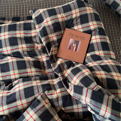 Top-down view of the vintage plaid cotton muslin bedding with a magazine on top, showcasing the high-quality, textured, and rustic aesthetic of the material.