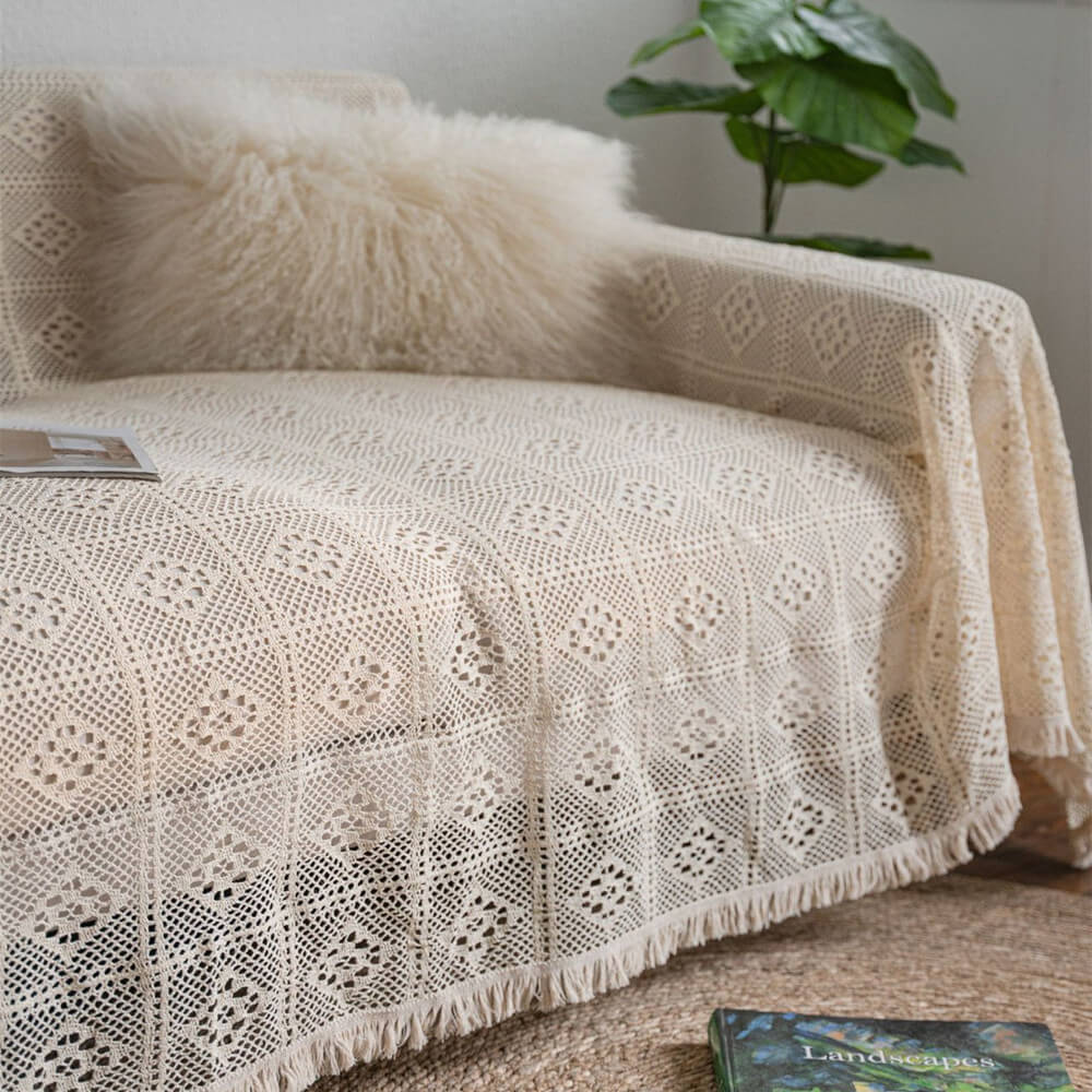 Vintage crochet lace sofa cover with tassel trim, cozy cushion, and plant in living room