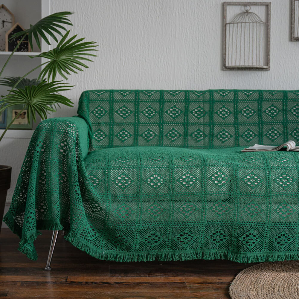 Green crochet lace sofa cover with tassel trim in a cozy living room setting