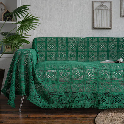 Green crochet lace sofa cover with tassel trim in a cozy living room setting