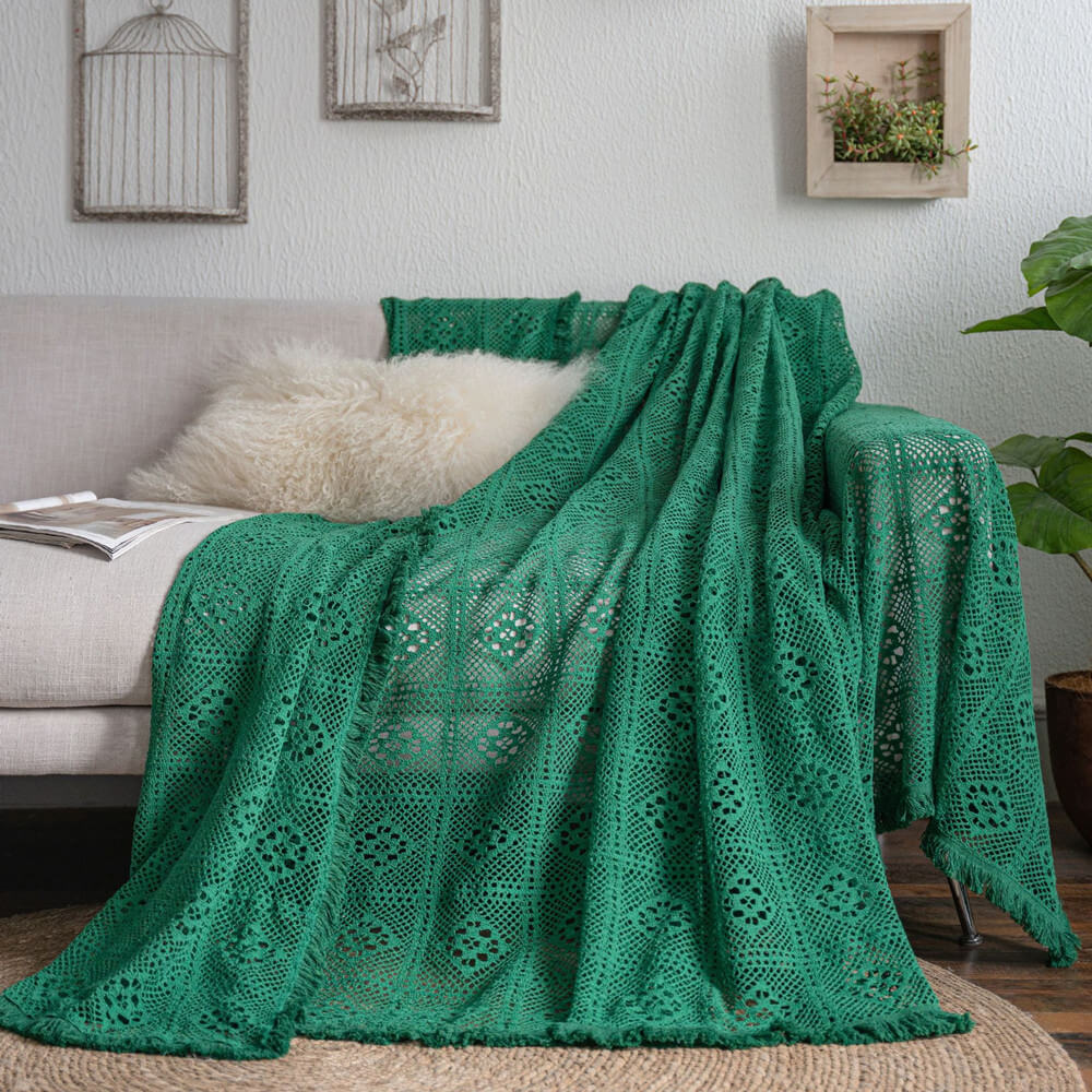 Green crochet lace sofa cover with tassel trim on beige sofa, featuring cozy, sustainable home decor.