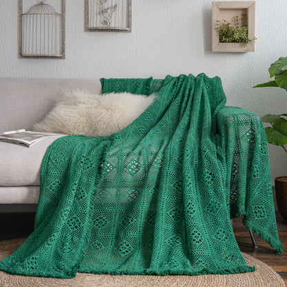 Green crochet lace sofa cover with tassel trim on beige sofa, featuring cozy, sustainable home decor.