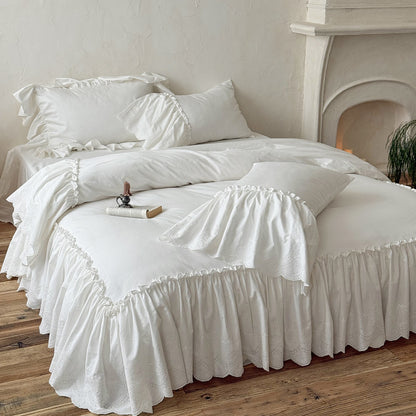 White cotton bedding set with ruffled trim on a cozy bed in a rustic bedroom setting