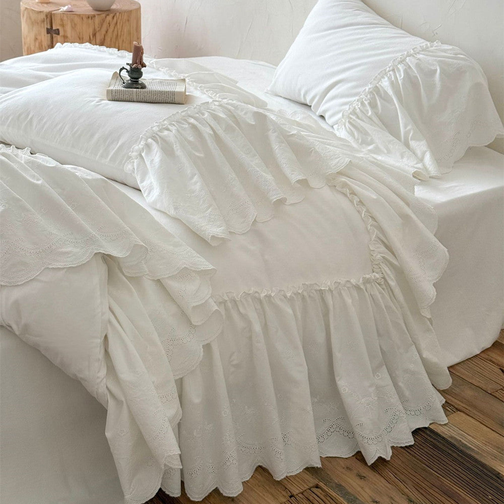 White cotton bedding set with ruffled trim on a bed in a cozy, rustic bedroom