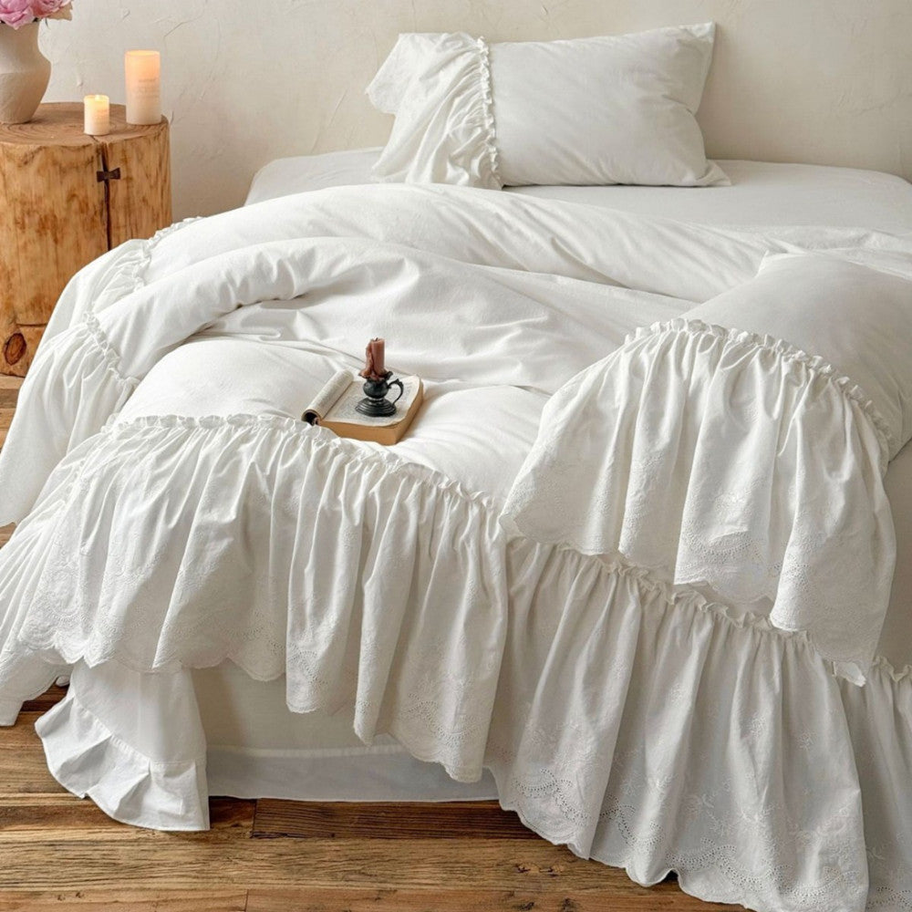 White cotton bedding set with ruffled trim on a cozy bed in a rustic bedroom