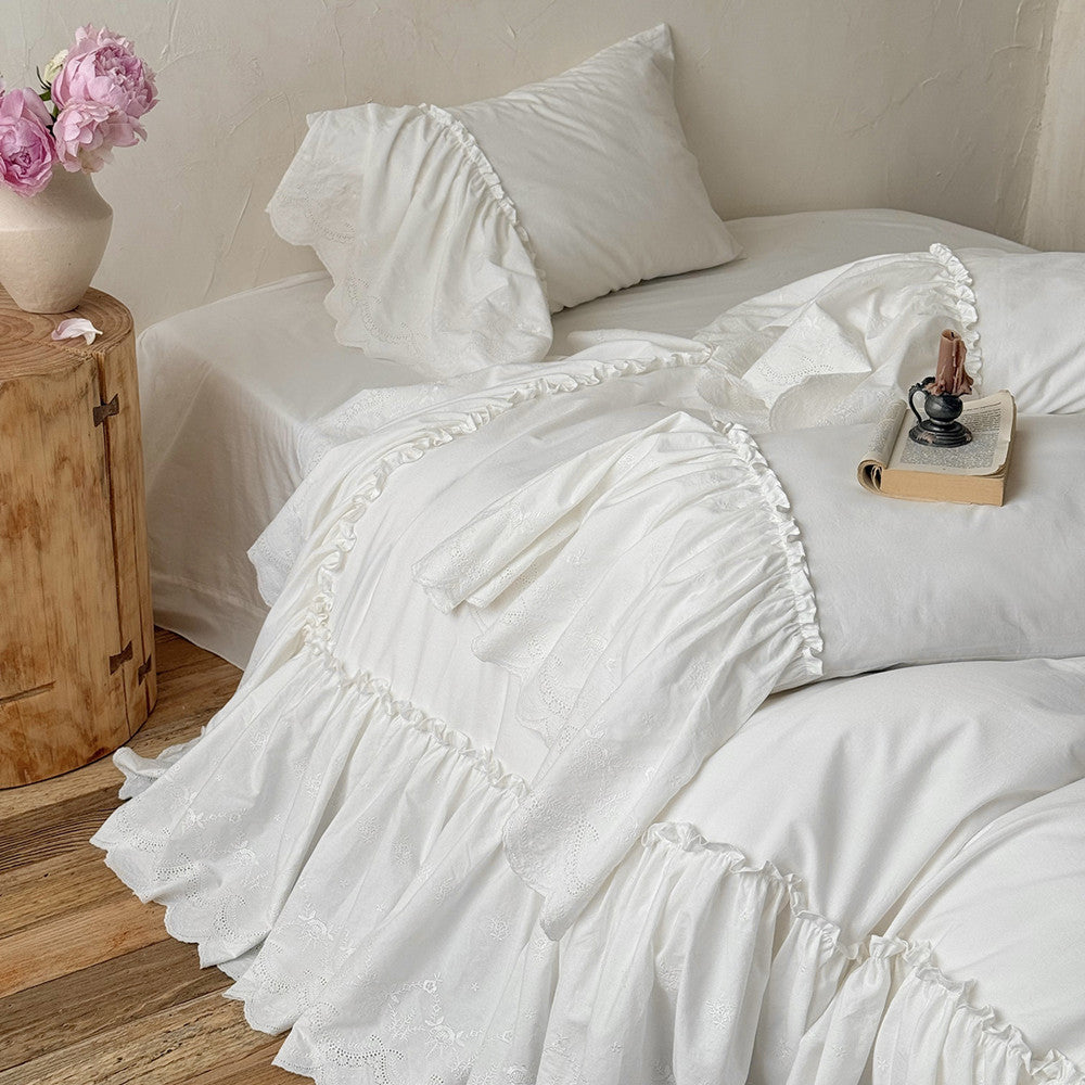 White cotton bedding set with ruffled trim in a cozy bedroom, floral vase on nightstand