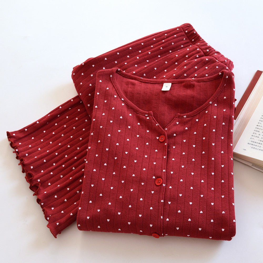 Red cotton pajama set for women with white heart print and long sleeves, folded on a table.