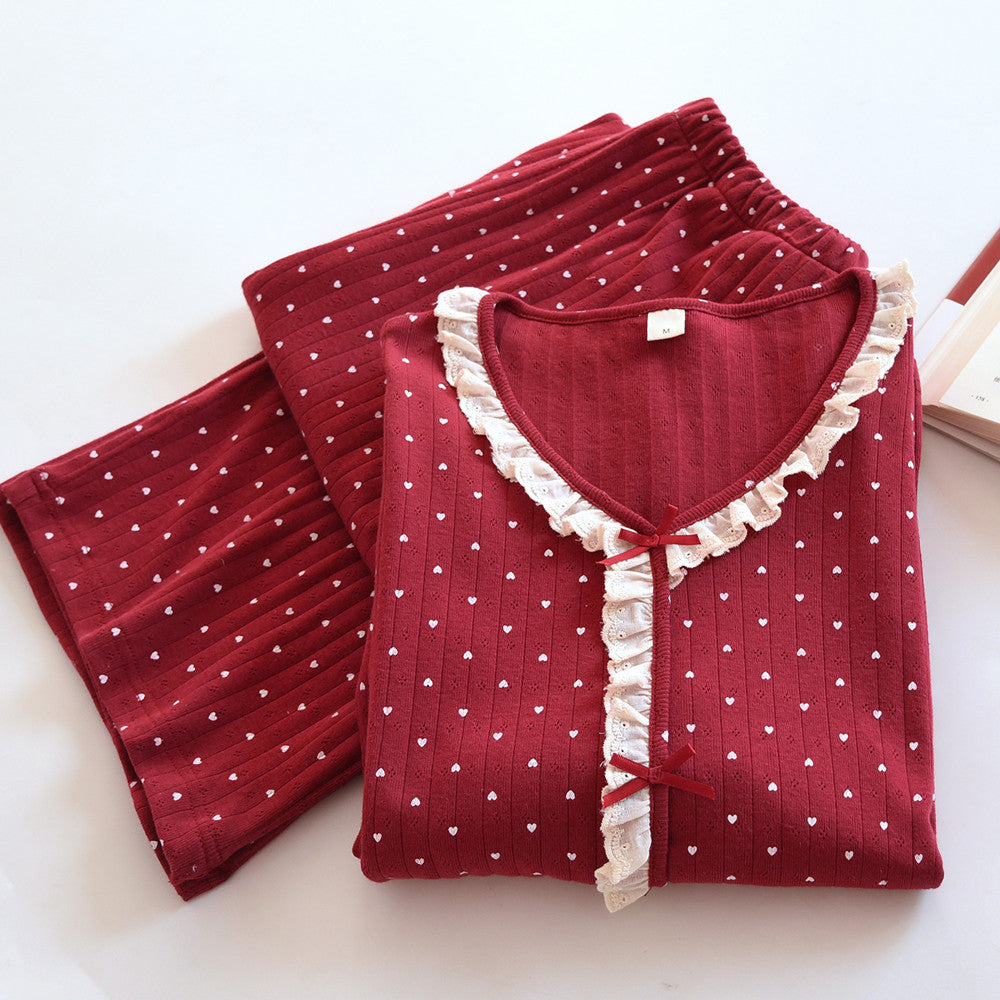 Red cotton pajama set with white heart print and lace trim, folded on a white surface.