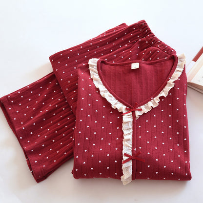 Red cotton pajama set with white heart print and lace trim, folded on a white surface.
