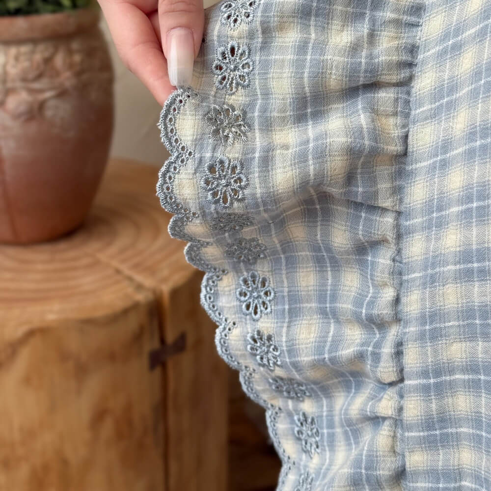 Detail shot of ruffled edge and plaid cotton muslin on bedding set
